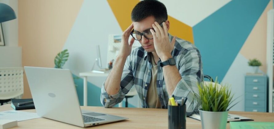 Vermoeide man bij laptop wrijft over zijn ogen tijdens beeldschermwerk