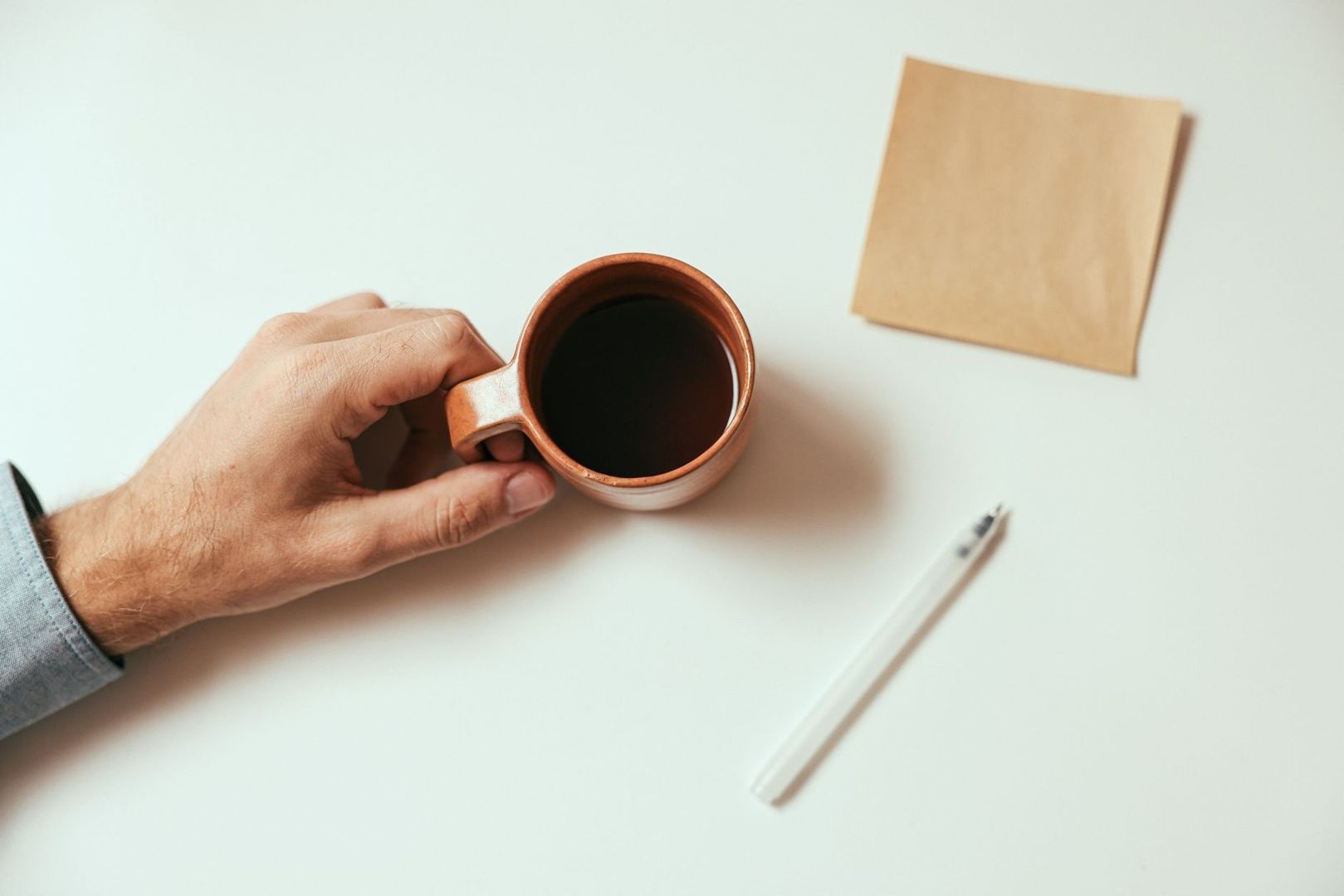 Hand houdt een kop koffie vast tijdens een korte pauze aan een bureau