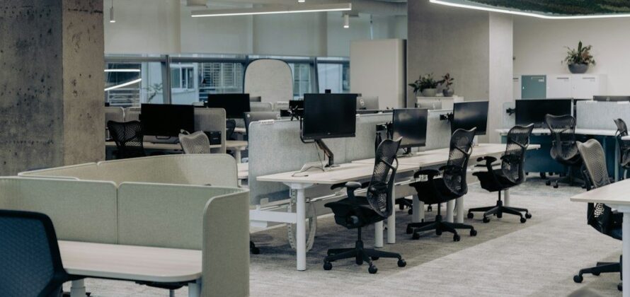 Rustig modern kantoor met bureaus, computerschermen en lege bureaustoelen