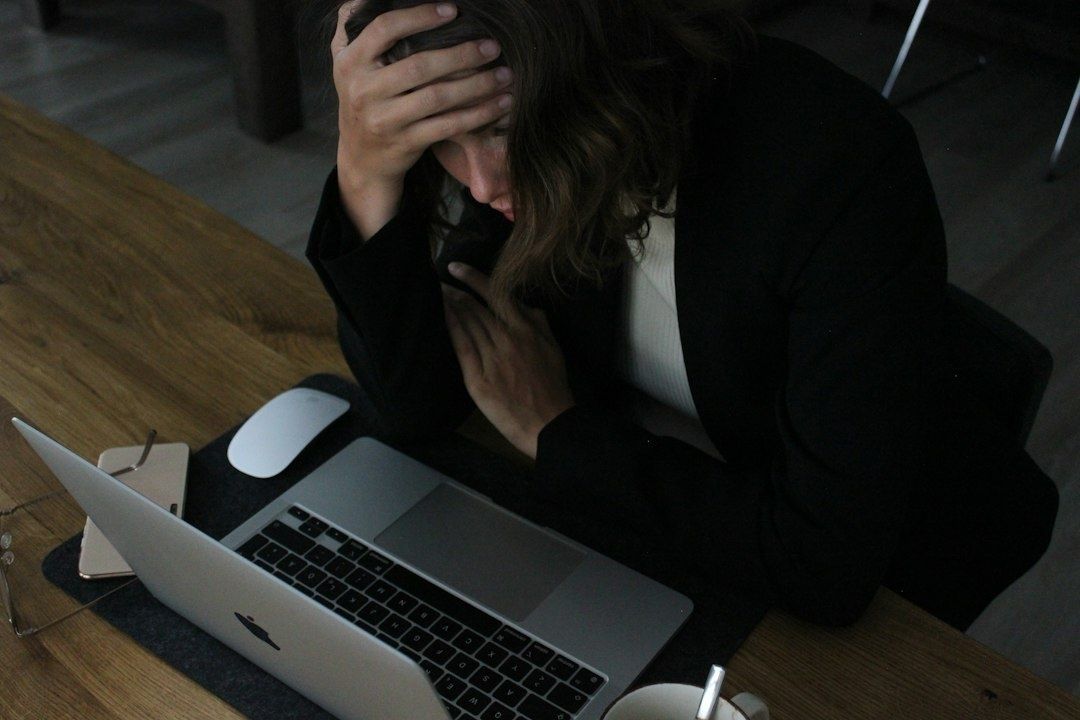 Gestreste vrouw aan laptop met haar hand op haar hoofd